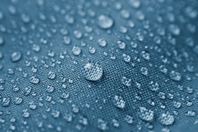 Close-up of water droplets beading on a durable water repellent treated jacket fabric