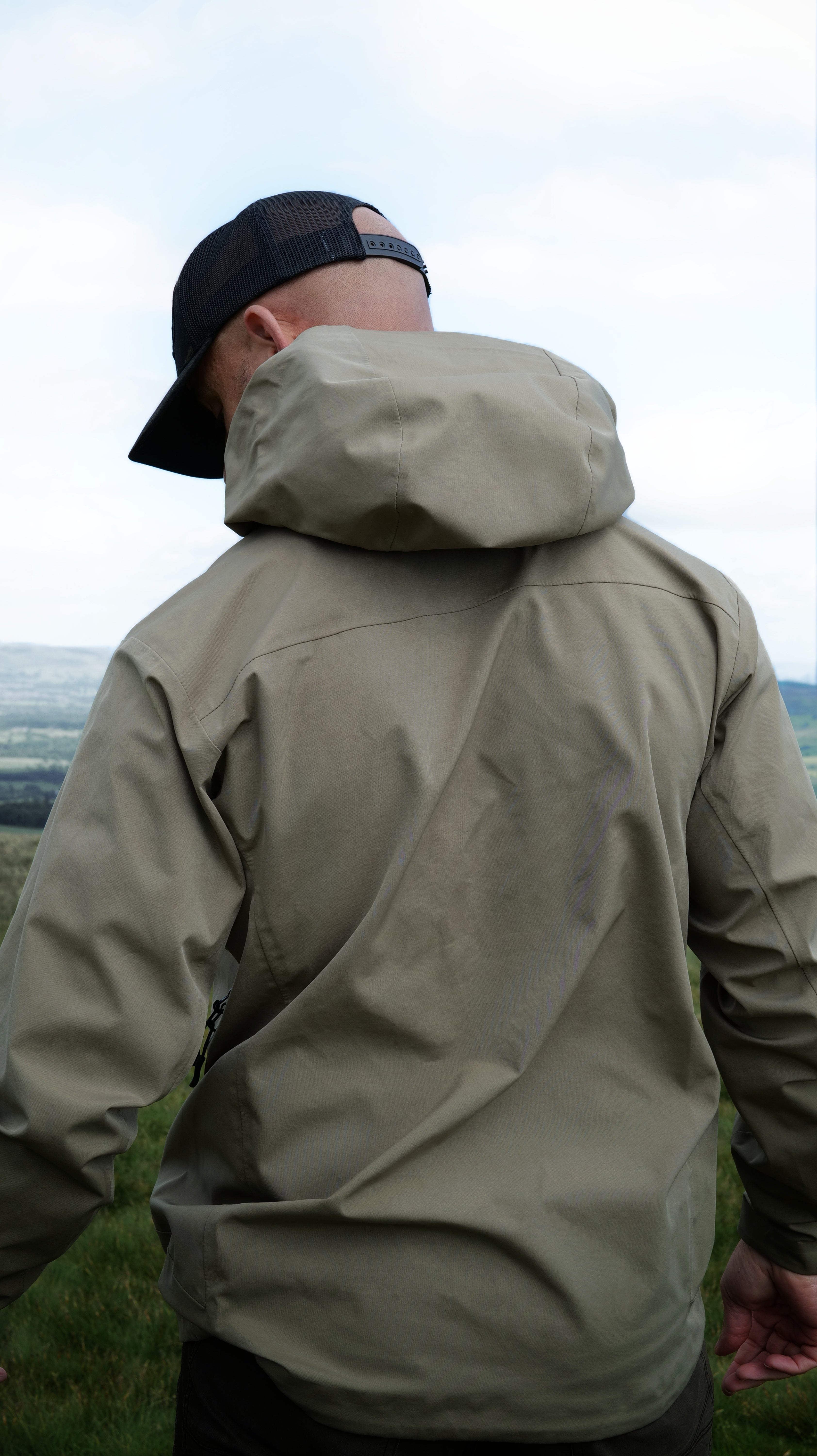Man wearing the Halfell Fellguard Hardshell Jacket from behind with the hood up, on the fells