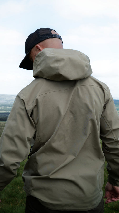 Man wearing the Halfell Fellguard Hardshell Jacket from behind with the hood up, on the fells
