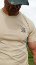 Man wearing the Halfell Origins T-Shirt in sand, close-up of the embroidered beetle logo on the chest